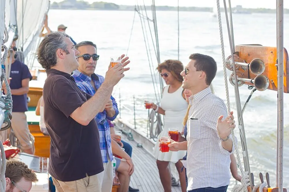 A group of people are engaging in a conversation while holding drinks aboard a sailboat