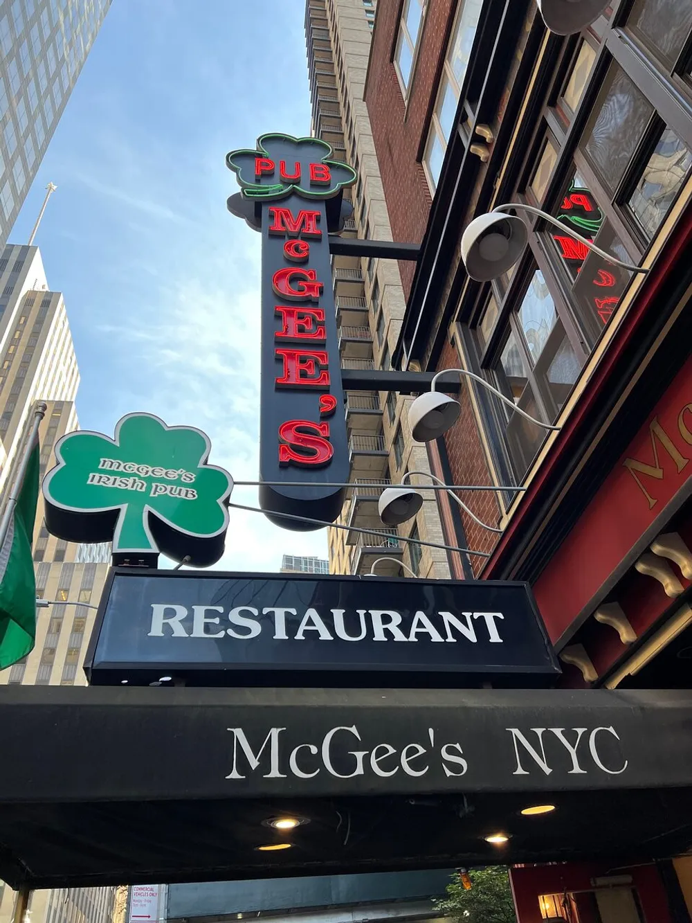 The image shows the exterior signage of McGees Irish Pub and Restaurant in New York City with multiple green shamrock designs and neon lights