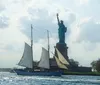 Passengers on a sailboat are capturing photos of the Statue of Liberty on a sunny day