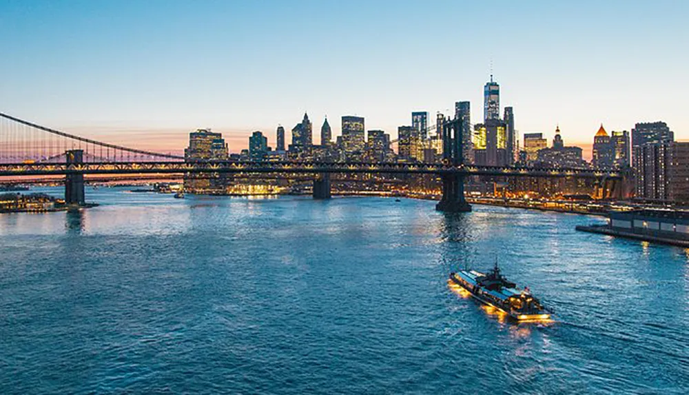 This image captures a twilight cityscape featuring a bridge over a river with a tugboat and a backdrop of illuminated skyscrapers under an evening sky