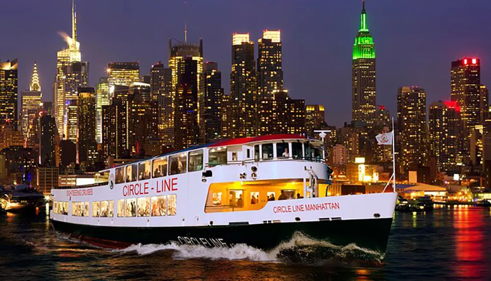 A tour boat named Circle Line Manhattan cruises in front of the illuminated New York City skyline at dusk