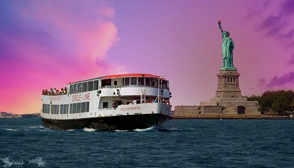 A sightseeing boat full of tourists passes by the Statue of Liberty against a backdrop of a vividly colored sky