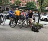 A person wearing a helmet and sunglasses is riding a road bike on a street alongside other cyclists in casual attire