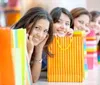 A group of cheerful women is peeking out from behind colorful shopping bags possibly after a fun shopping spree