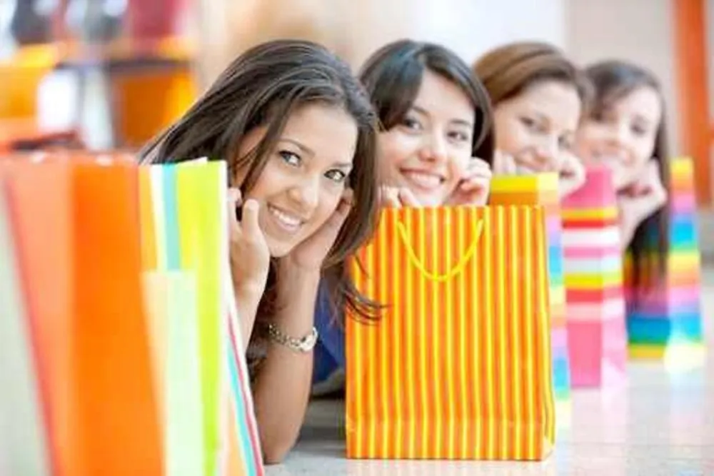 A group of cheerful women is peeking out from behind colorful shopping bags possibly after a fun shopping spree