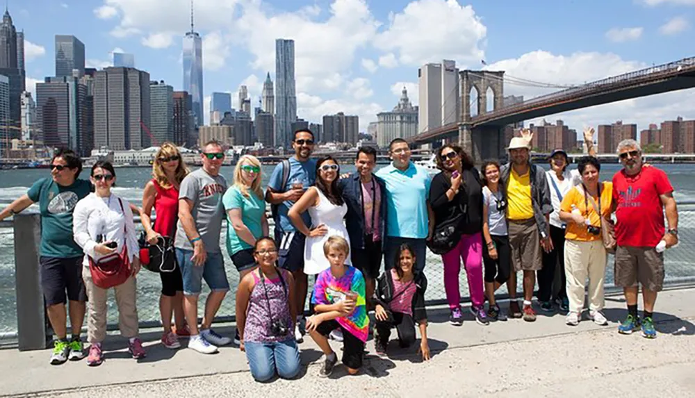 A diverse group of people poses for a photo with the Brooklyn Bridge and the Manhattan skyline in the background