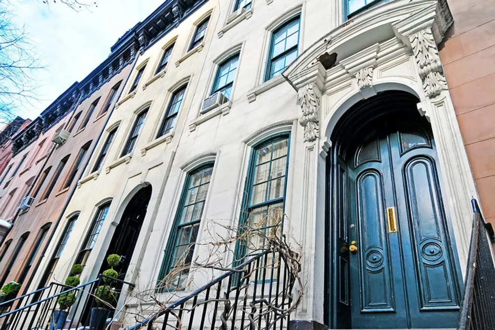 The image shows a row of colorful historic townhouses with an ornate dark doorway capturing the architectural charm of an urban neighborhood