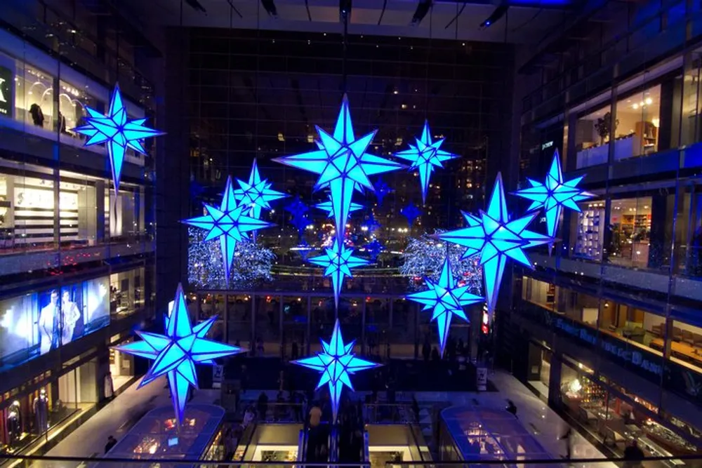 The image shows a vibrant indoor space adorned with large illuminated star-shaped decorations creating a festive atmosphere