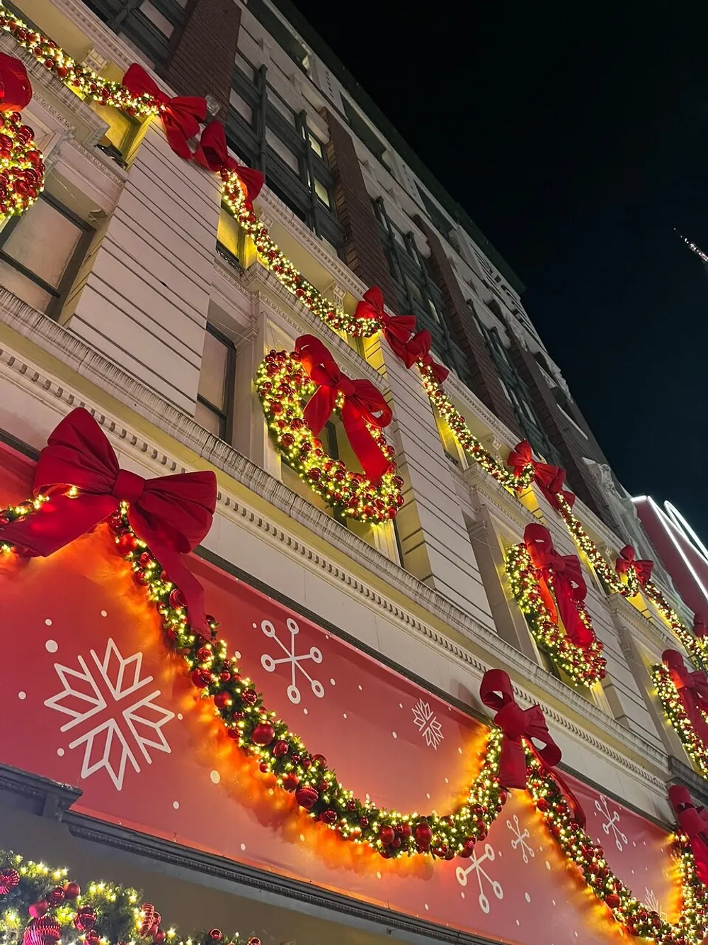 The building is adorned with festive Christmas decorations featuring wreaths red bows and strings of lights along its exterior