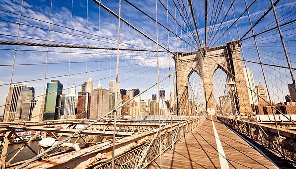 The image shows a sunny day on the Brooklyn Bridge with its distinctive cable design overlooking the Manhattan skyline