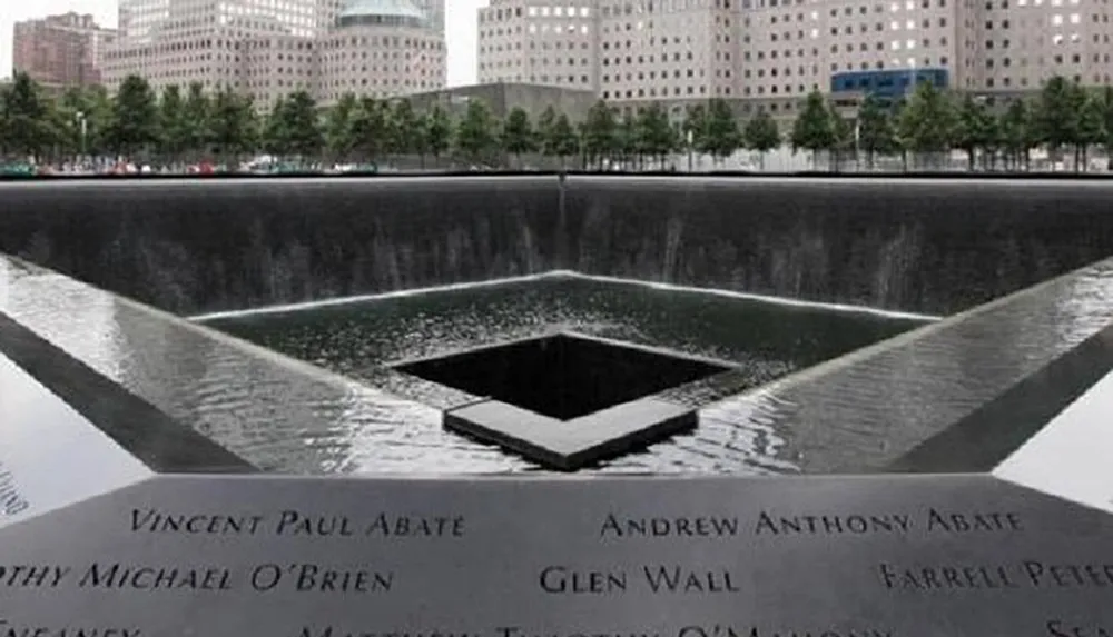 The image shows one of the two reflecting pools of the National September 11 Memorial in New York City which commemorates the victims of the September 11 attacks with the names of those who perished inscribed around the pools edge