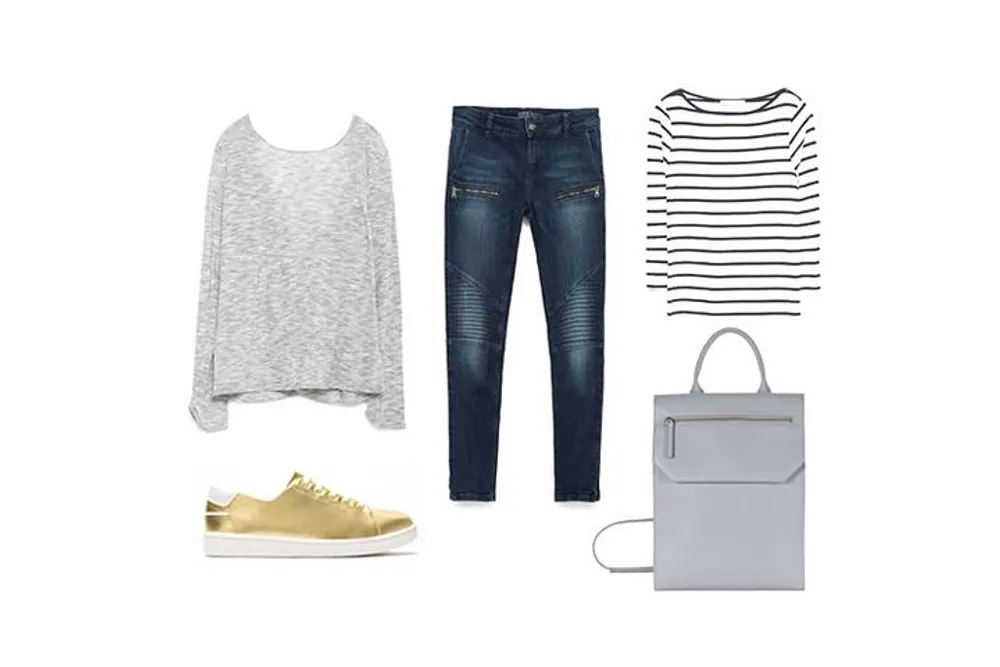 The image shows a flat lay of a casual fashionable outfit including golden sneakers blue jeans a grey long-sleeve top a striped shirt and a grey backpack