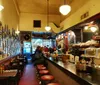 The image depicts the cozy interior of a classic diner with patrons seated at the counter and framed pictures lining the wall