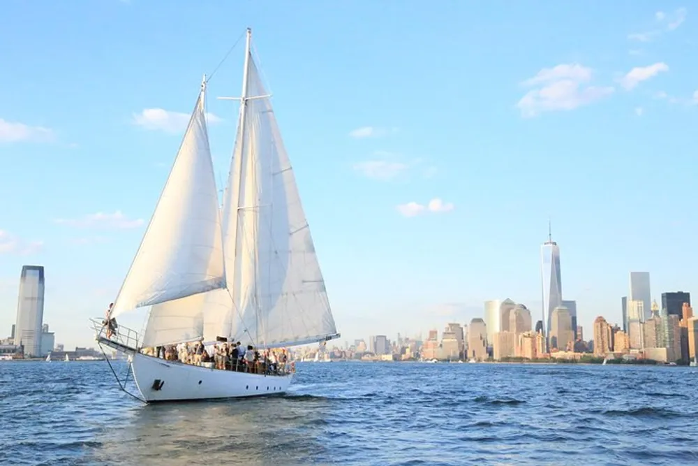 A sailboat filled with people is cruising on calm waters with a backdrop of a modern city skyline