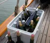 A staff member is presenting a bottle of wine to guests aboard a sailboat indicating a leisurely and social atmosphere
