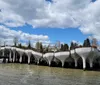 Two individuals are smiling for the photo in front of a modern water structure on a sunny day