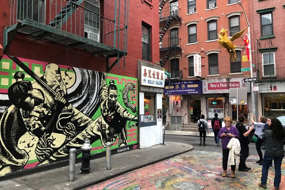 A vibrant street corner shows people a colorful mural and eclectic urban elements including a golden sculpture on a post