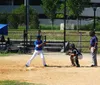 A batter catcher and umpire are positioned and ready for a pitch in a sunny baseball game