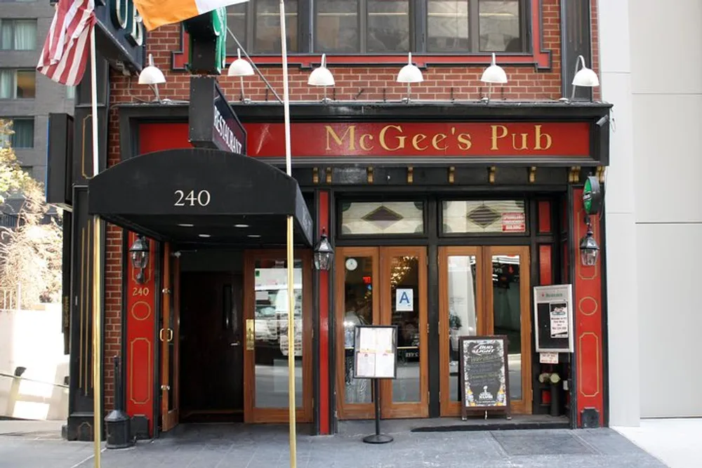 The image shows the facade of McGees Pub a traditional establishment with a red brick exterior displaying American and Irish flags and a prominent sign above the entrance