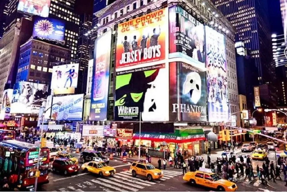 The image shows a vibrant and bustling Times Square at night illuminated by bright billboards and alive with the iconic yellow cabs of New York City