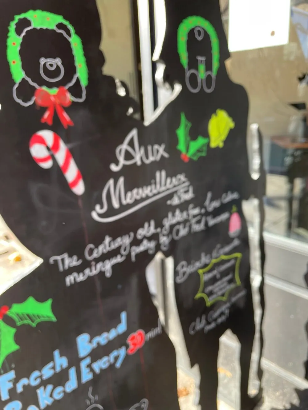 The image features a festive-looking blurred blackboard sign with colorful chalk illustrations and text that seems to be advertising fresh bread and other specialties with a candy cane and Christmas decorations suggesting a holiday theme