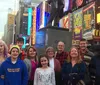 A group of people are posing for a photo in Times Square surrounded by bright billboards and city lights