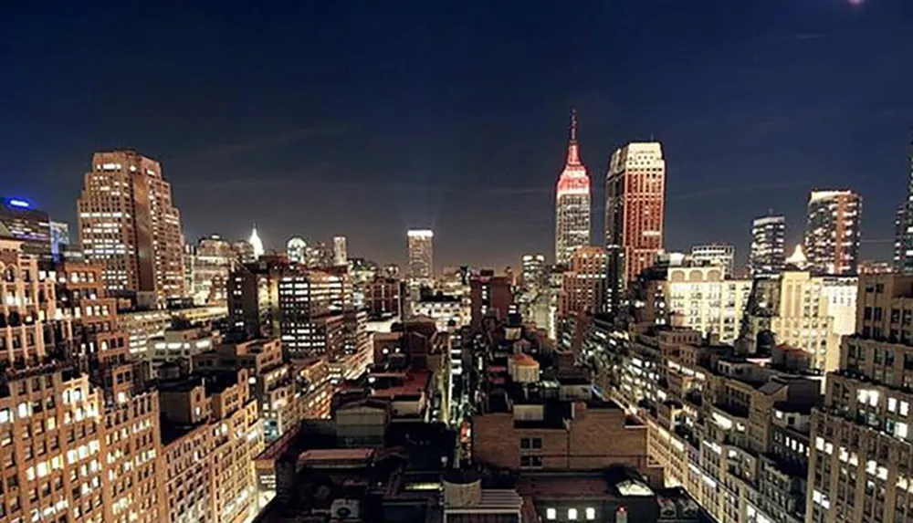 The image showcases a bustling urban skyline at night with illuminated buildings and a prominent skyscraper lit up in red and white