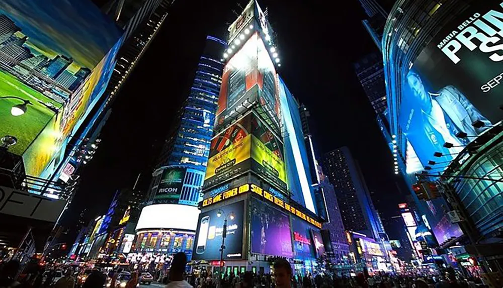 The image shows a bustling Times Square at night illuminated by numerous vibrant billboards and crowded with people