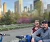 Two people are smiling for a photo while sitting in a pedicab on a city street