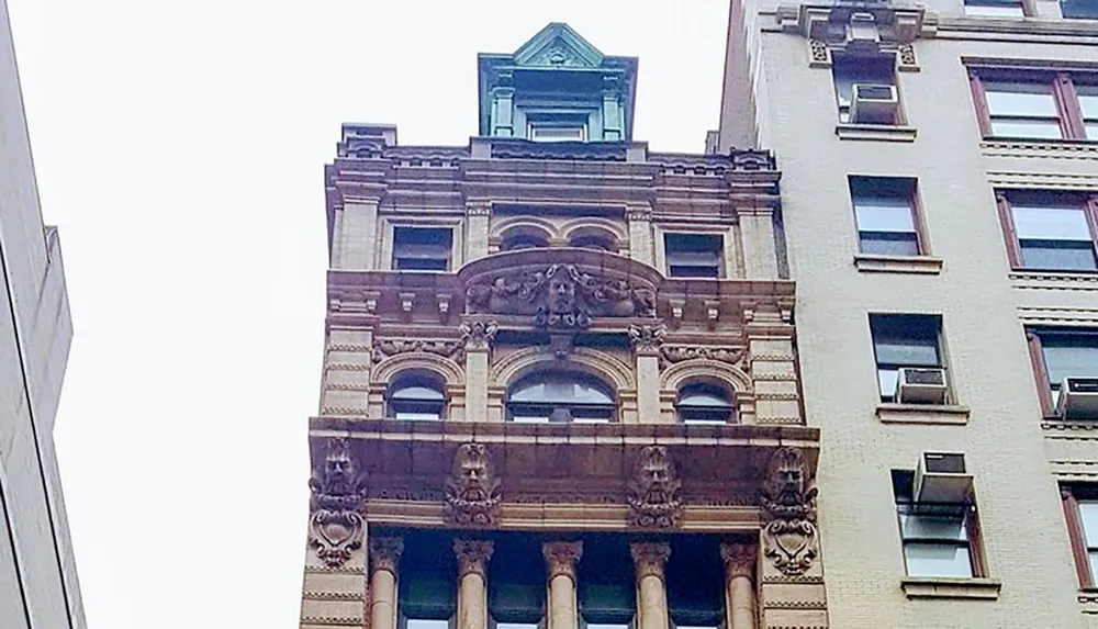 The image shows a detailed ornate building facade next to a plainer building typical of contrasting architectural styles in an urban environment