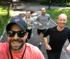 Four people one taking a selfie are smiling and jogging on a sunny day on a park path