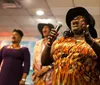 A group of women passionately singing in a choir with one in the foreground holding a microphone