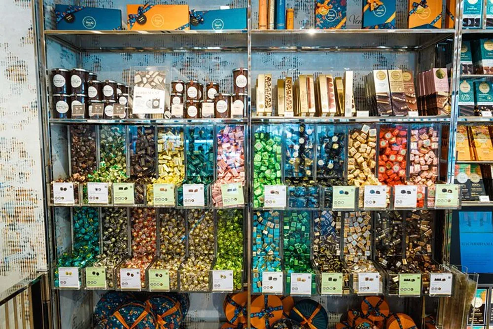 A shelving display is filled with an assortment of colorful candies and chocolates in a retail store