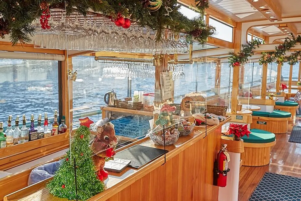 The image shows a festively decorated bar onboard a boat adorned with Christmas decorations and a view of the water outside