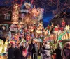 A group of people gathers in front of an elaborately decorated house with an abundance of colorful Christmas lights and festive ornaments creating a vibrant holiday atmosphere