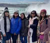 A group of five people pose for a photo with a misty backdrop that suggests the presence of a large waterfall or rapid waters possibly near a tourist attraction