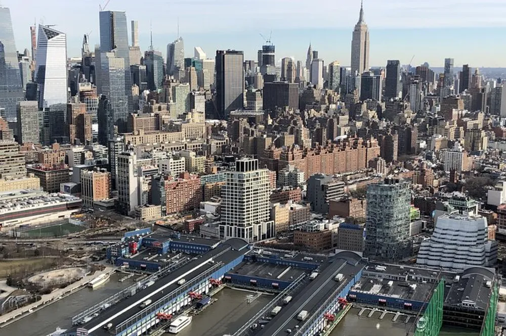 The image is a high angle view of a dense urban skyline with numerous skyscrapers under a blue sky highlighting the architectural diversity of a bustling city