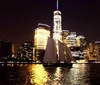 A sailboat is silhouetted against the illuminated skyline of a city at night