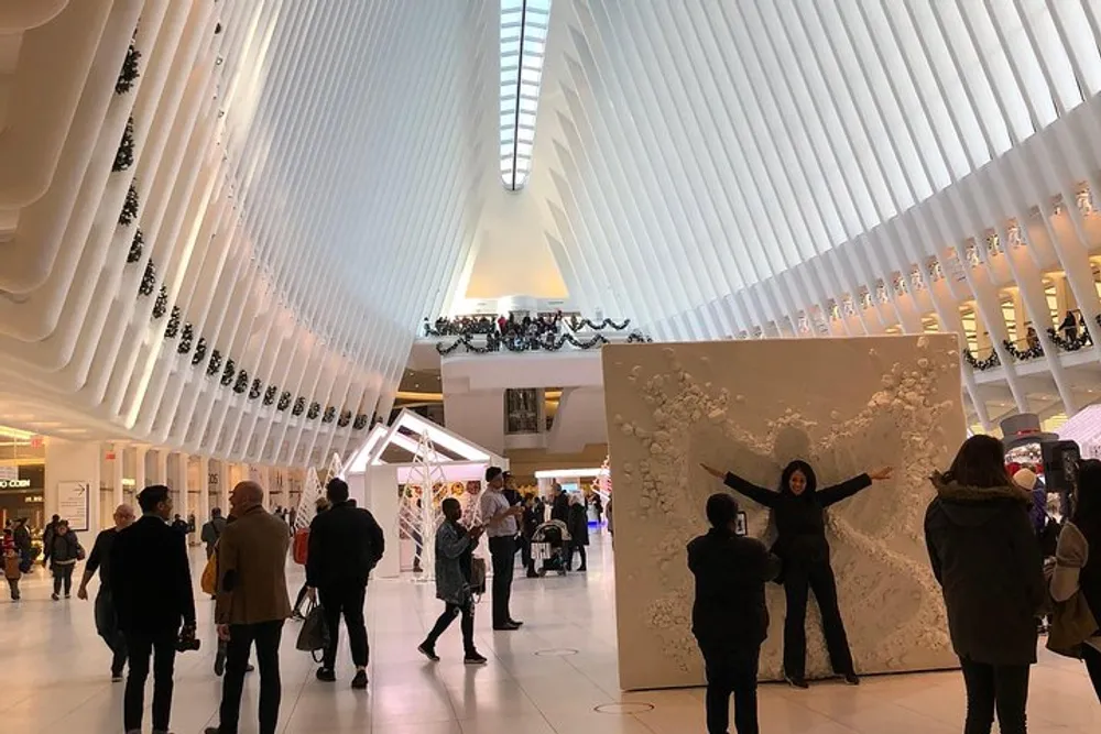People are walking and taking photos inside a modern building with an undulating white ribbed ceiling