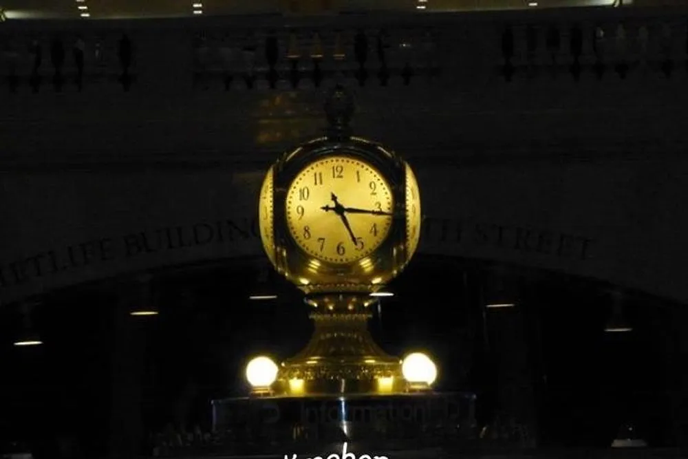 The image shows an iconic golden clock illuminated and prominently displayed indoors with the inscription Information visible below it