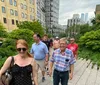A group of people is enjoying a walk on a path surrounded by greenery in an urban environment