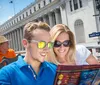 A tour guide is assisting tourists with a map beside a Big Bus New York tour bus with Times Square in the background