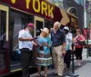 A tour guide is assisting tourists with a map beside a Big Bus New York tour bus with Times Square in the background