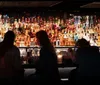 A group of people are posing for a photo with drinks at a rooftop venue at night with the illuminated skyline of a city in the background