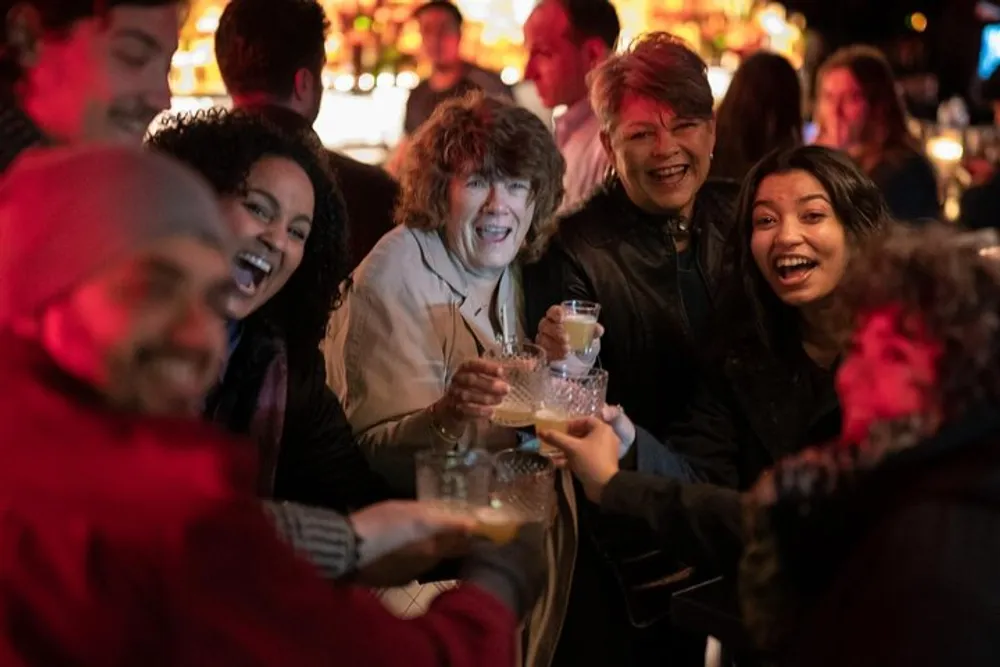 A group of happy people are toasting with drinks in a lively bar setting