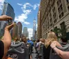 Tourists on an open-top bus tour are seen capturing photos of cityscapes and skyscrapers on a sunny day