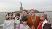 A group of people are posing for a photograph in front of the Statue of Liberty.