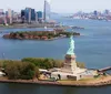 An aerial view of the Statue of Liberty with the New York City skyline in the background and Ellis Island nearby