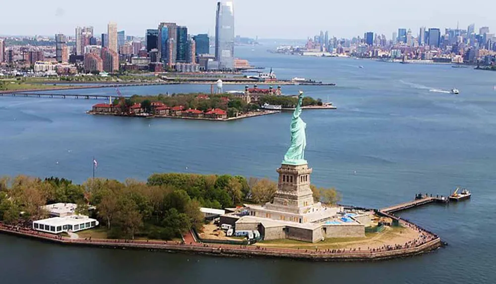 An aerial view of the Statue of Liberty with the New York City skyline in the background and Ellis Island nearby