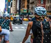 Two cyclists are smiling for the camera on a tree-lined urban street